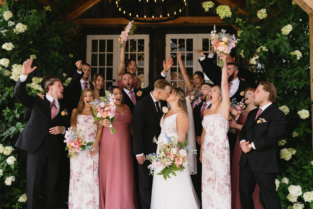 wedding party cheering with flowers at the Promise Gardens of the Adirondacks