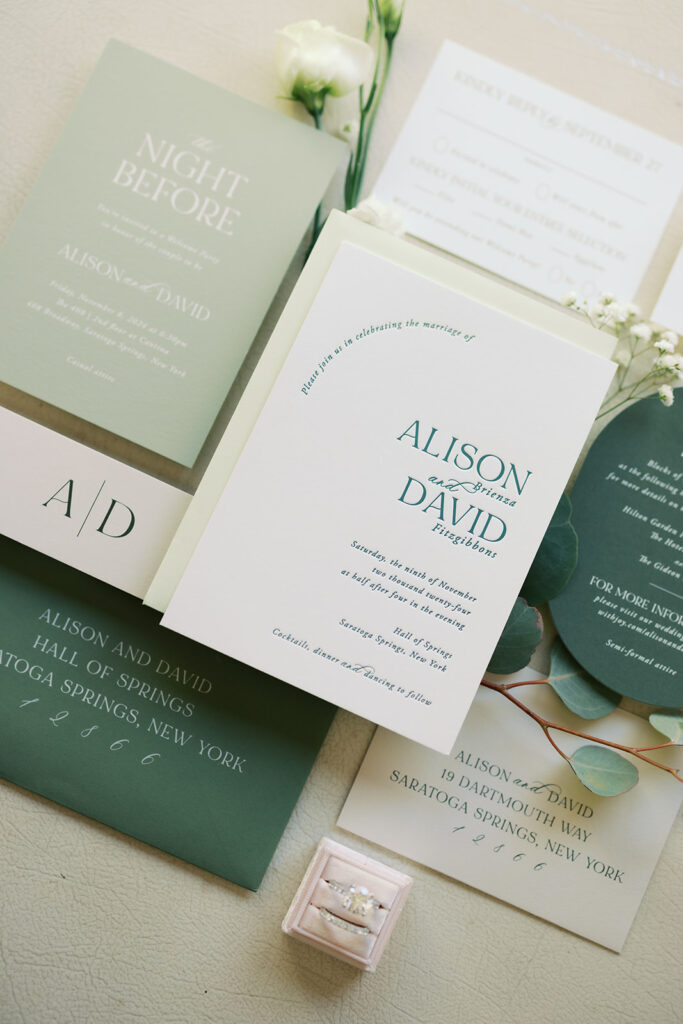 Flat lay that includes invitation to wedding and invitation to the rehearsal dinner. 