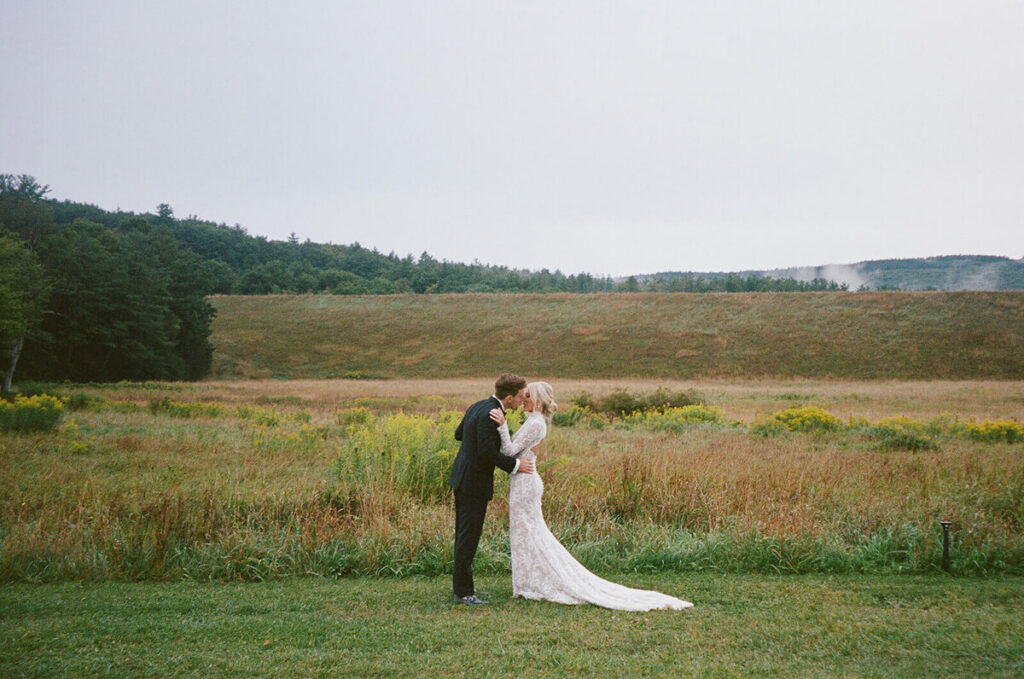 Bride and groom embracing in an open field at a Hayfield Catskills wedding in Windham, New York.
