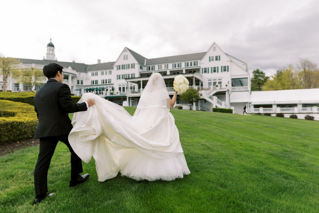 Bride and groom walking toward a grand white estate venue during a full-service wedding in Hudson Valley, New York.